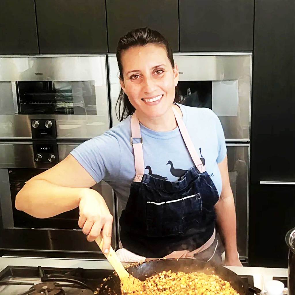 Marlene, CEO of Healing Arts Massage & Wellness Center in a modern kitchen with an apron on making a healthy meal while living her best life!